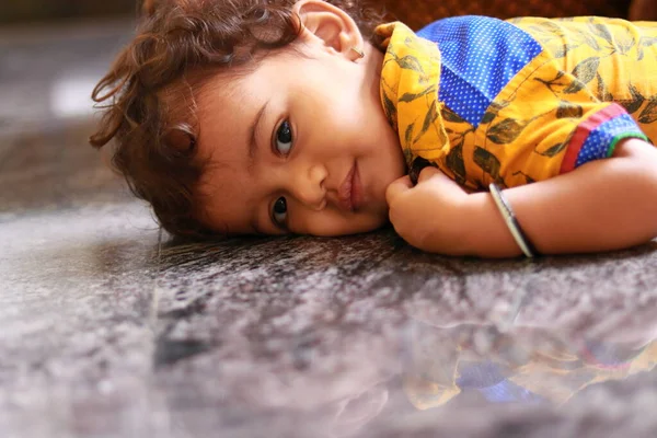 一个小孩看着黑色大理石地板上的相机 — 图库照片