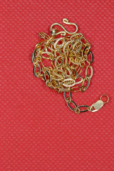 Bright gold long chain on red background