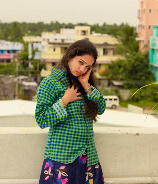 Seksi ve romantik Hintli kız, ıslak gözlü, yeşil gömlekli, saçları kırmızı ve muhteşem kırmızı dudaklarıyla dağınık ve açık havada evin çatısında duruyor.