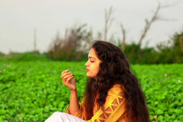 一个美丽的印度女人坐在那里 手里拿着一株植物的叶子在研究它 — 图库照片