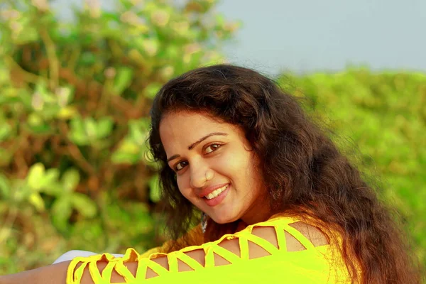 Güzel bir yüzü ve sarı süslü bluzu olan mutlu bir Hintli kadının yakın plan portresi.