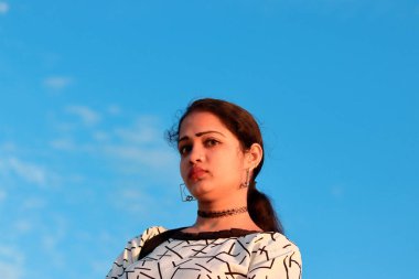 Düşük açılı, yakından çekilmiş mavi gökyüzü portresi. Kadının arkasında küçük beyaz bir bulut var.