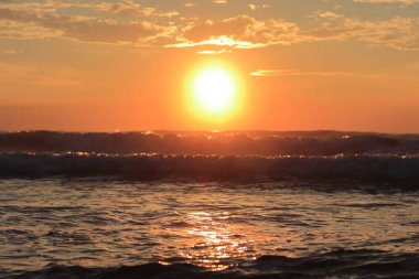 Seçici odak, sabah gündoğumunda, parlak güneşin devasa parlak ışınları dev okyanusun yükselen dalgalarını karşılar.