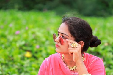 Hintli genç, çekici, şık bir sarışının yakın plan portresi. Yazın doğada poz vermiş. Geleneksel moda elbisesi.