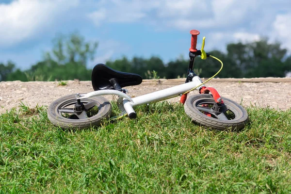 children\'s bike lies on the grass. Abandoned bike