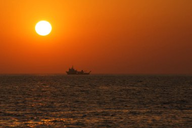 Güneş ve geminin silueti ile Turuncu güzel deniz manzarası