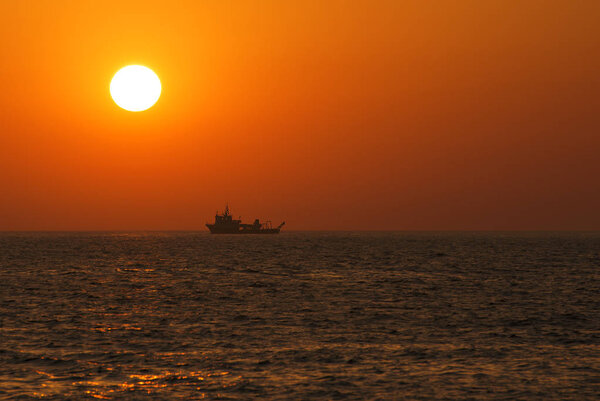 Orange beautiful seascape with sun and the silhouette of the ship