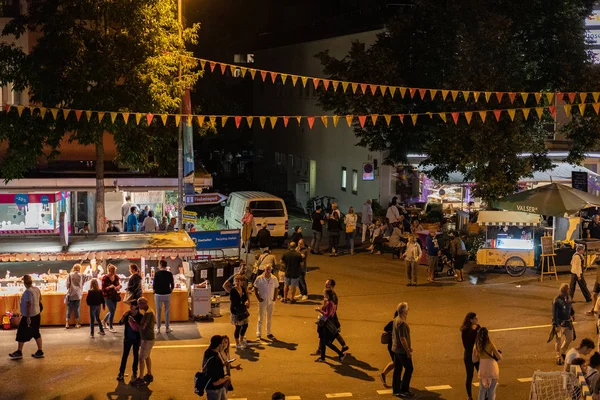 Stadtfest Brugg 24 Ağustos 2019. sokak fotoğrafçılığı. Sokak festivalinin gece fuar alanında insanlarla dekore edilmiş girişi.