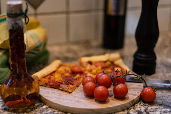 新鲜的番茄、油和胡椒粉磨在切板上的比萨饼. — 图库照片