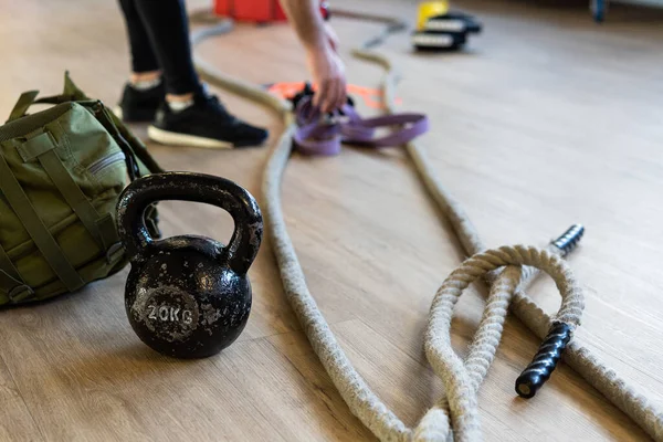 Eğitim kampı için jimnastik malzemelerini hazırlıyorum. Spor salonundaki su ısıtıcısı, halat ve kum torbasıyla egzersiz yapıyorum. Arka planda eğitmen bacakları.