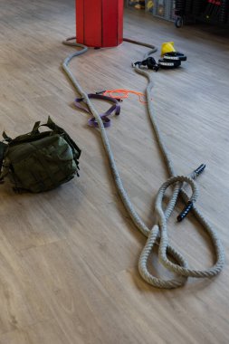 Gym equipment for boot camp and work out with kettle bell, rope, sandbag in gym hall on the floor. Vertical shot. clipart
