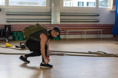 Eğitmen diz çöküp ayakkabı bağcıklarını sırt çantası ve eğitim maskesiyle bağlıyor. Eğitime başlıyorum. Eğitim kampı ve beden eğitimi konsepti için..