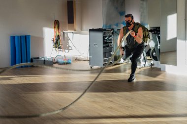 Antrenman maskesi takan bir sporcu. Kapalı bir yerde, meşe zemininde, güneş ve gölgeyle. Eğitim kampı konsepti.