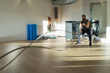 Antrenman maskesi takan bir sporcu. Kapalı bir yerde, meşe zemininde, güneş ve gölgeyle. Eğitim kampı konsepti.