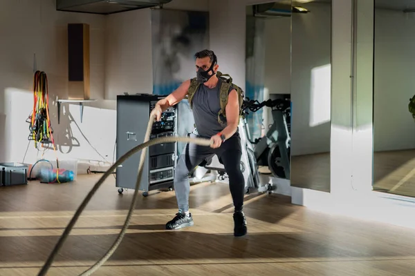 Antrenman maskesi takan bir sporcu. Kapalı bir yerde, meşe zemininde, güneş ve gölgeyle. Eğitim kampı konsepti.