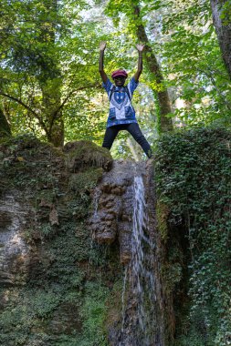 Parlak güneşli bir günde, kırmızı şapkalı, altın tarlada duran siyah bir kadın. Linn Boezberg, İsviçre 'de hasat edilen mısır tarlasında gezen bir kadın..