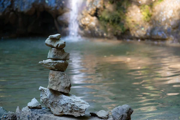 Stacked pile of stones in front of reflecting lake and cascade. Scenie for meditation concept. Biggest waterfall of canton Aargau, in Linner Boezberg, Switzerland. — Stock Image Stacked Pile Stones Front Reflecting Lake Cascade Scenie Meditation Concept Stock Photo