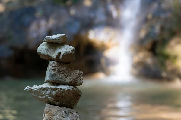 Stacked pile of stones in front of reflecting lake and cascade. Scenie for meditation concept. Biggest waterfall of canton Aargau, in Linner Boezberg, Switzerland. — Stock Image Stacked Pile Stones Front Reflecting Lake Cascade Scenie Meditation Concept Stock Photo