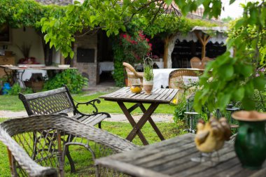 Bahçede dinlenmek için sandalye ve masa duruyor.