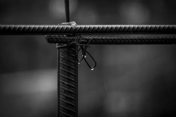 Metal fittings connected with wire. Rainy weather with water drops. Black and white photo.