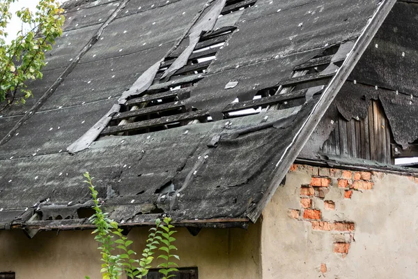 Damaged roof on an abandoned house that needs repair. Big holes in the old roof.