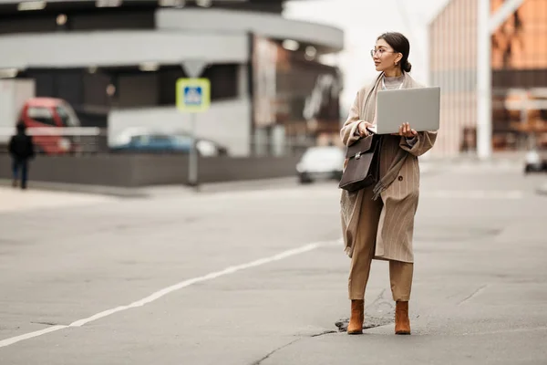 商务区中央站着一位漂亮的亚洲女商人 身穿长衫 手里拿着笔记本电脑 — 图库照片