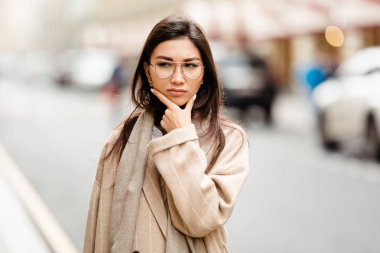 Asya görünümlü bir iş kadını yeni fikirler üretiyor ve caddenin ortasında dururken çenesini tutuyor.