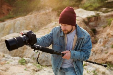 Videographer stabilizing monopod shoots wildlife in the evening sun