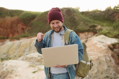 A successful freelancer with a laptop in his hands enjoys the work done while away from the city