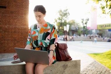 Freelancer girl sitting in the Park and typing notes tasks to be done