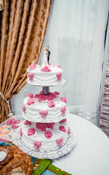 Tall wedding white with pink cake, newlyweds figurines