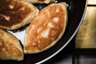 Gaz ocağının üstünde duran tavadaki taze turtalar, üst manzara.