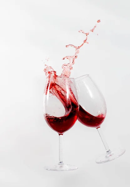 A couple of wine glasses splashing with red wine on them