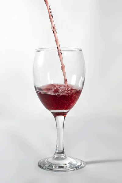 在酒杯上倒红酒 冻结运动 同时在右侧溅起杯影 — 图库照片