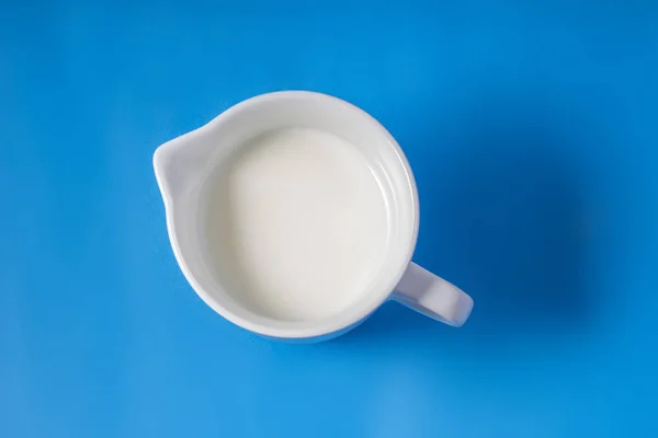Porcelain White Creamer Dispenser Pitcher with cream on a blue background — Stock Photo, Image
