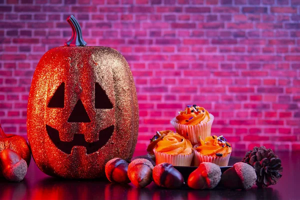 Halloween dynia z Halloween babeczki i ozdoby z czerwonym oświetleniem — Zdjęcie stockowe
