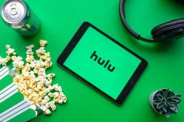 Calgary, Alberta. Kanada mı? Haziran 12020. Ekranda Hulu logosu olan, patlamış mısır ve kulaklıklı yeşil arka planda bir iPad.