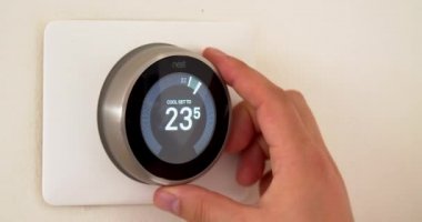 Calgary, Alberta, Kanada. 5 Haziran 2020. Yazın yüksek sıcaklıklarda, beyaz bir duvarda akıllı bir termostat kullanarak santigrat ölçümlerinde el ile enerji tasarrufu yapan bir kişi..