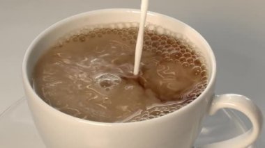 Gri arka planda bir fincan kahvenin üzerine yavaşça krema dök.