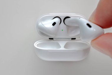 Calgary, Alberta, Kanada. Ağustos 2, 2020. Beyaz arkaplan üzerinde kablosuz şarj davası olan Apple Airpod 'ları elinde bulunduran birini kapat.