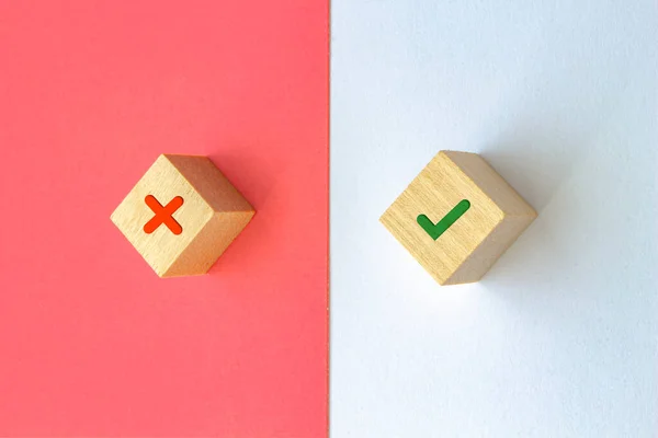 Wood cubes with an Ex and Check, wrong and right sign icons on a red and white background. Concept right and wrong.