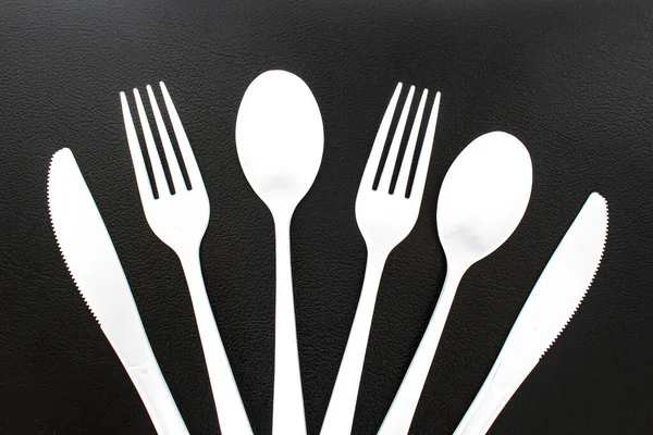 Single use white plastic cutlery on a leather background. Concept: Ban single use plastic