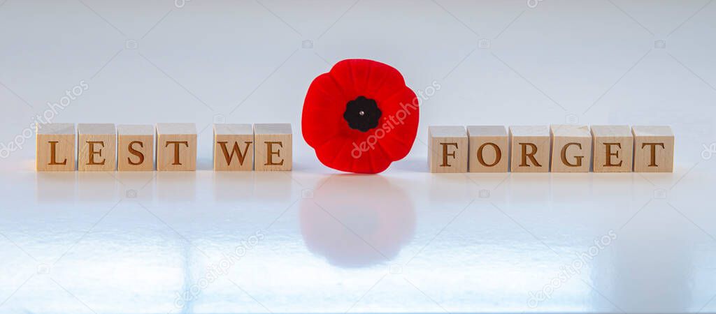 Lest we forget, text on wood blocks with a poppy flower. Concept: Remembrance Day.