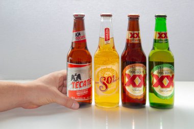 Calgary, Alberta, Kanada. 12 Ekim 2020. Meksika birası ve Meksika 'dan gelen çeşitli popüler biralar tutan biri. Tecate, Sol, Dos Equis bira şişeleri beyaz arka planda.