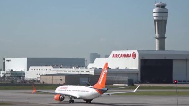 Calgary, Alberta, Kanada. Sep 3, 2025. Bir Kanada havaalanında Sunwing Boeing 737 taksisi, Air Canada hangarı ve arka planda kontrol kulesi, hareketli havacılığı gösteriyor..