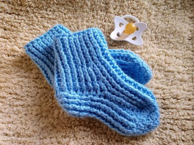 sarı arka planda mavi örme patikler ve emzik