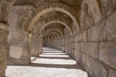 Türkiye 'nin Antalya kentindeki Roma Amfiteatrı Aspendos' un kemerli koridorlarından birinin güzel perspektifi. Önplanda ışık efekti olan güzel, dokulu duvarlar..