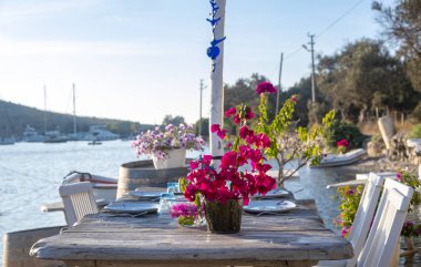 Deniz kenarındaki ahşap masa ve sandalyeler Gumusluk, Bodrum -Türkiye 'de deniz kıyısında açık bir kafe restoranı açıyor. Yaz tatili.