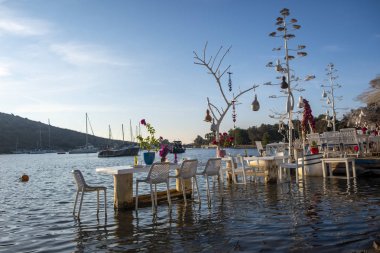 Gumusluk, Bodrum, Türkiye - 26 Eylül 2019: Yunanistan sınırı yakınlarındaki Bodrum Yarımadası 'nda Türkiye' nin Gumusluk köyündeki Ege kıyısındaki Yat ve restoranlar