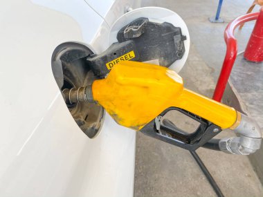 Benzin istasyonunda yakıt ikmali yapan küçük beyaz bir araba. Benzin istasyonunda yakıt ikmali yapılıyor.